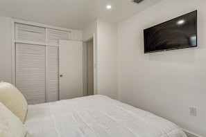 A bedroom with a bed, a television on the wall, and a closet with sliding doors. - FIU Basecamp: Miami Home w/ Fenced Yard! (Miami)