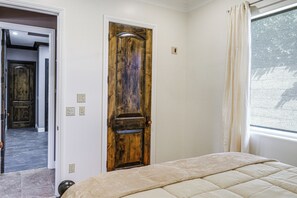 A bedroom with a wooden door, a bed with a beige duvet, a window with a curtain, and a doorbell. - Bakersfield Guest Suite, 11 Mi to Dtwn! (Bakersfield)