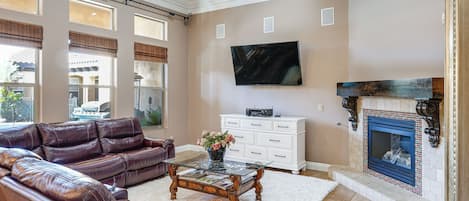 A living room with a leather sofa, a glass coffee table, a white cabinet, and a fireplace.