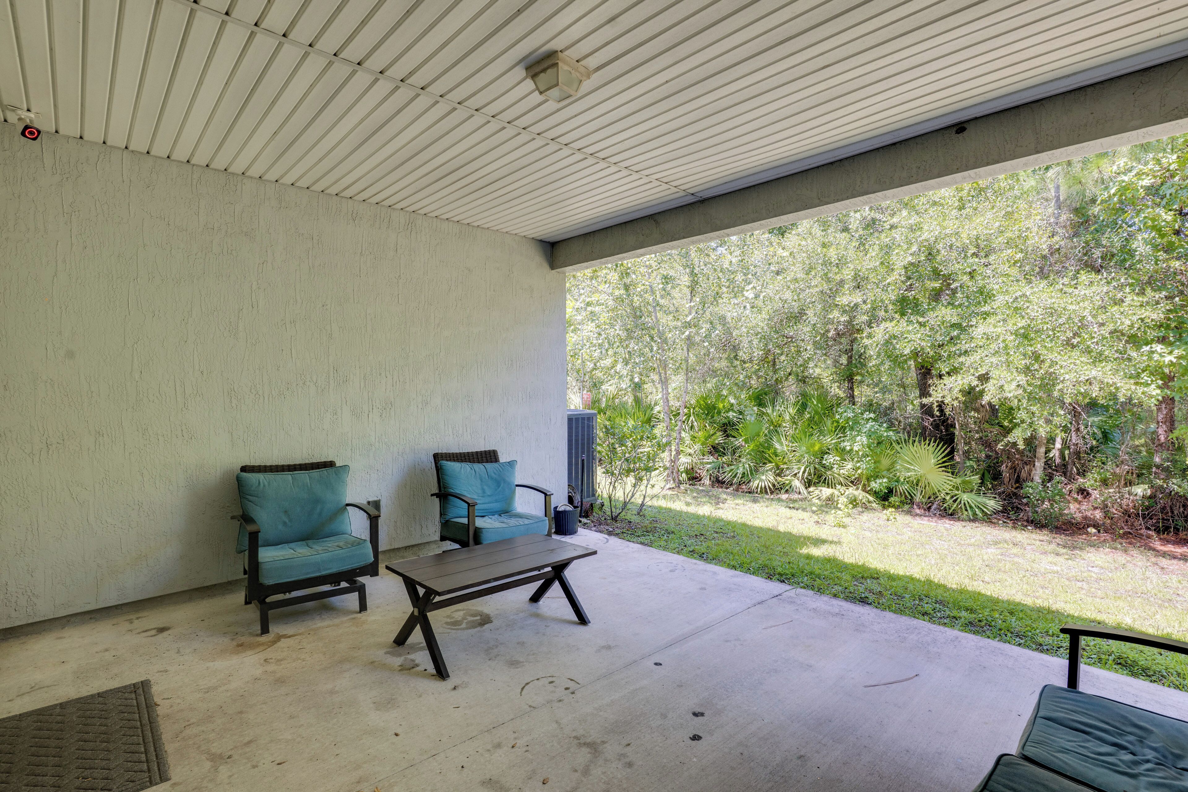 Un patio exterior con dos sillas y una mesa, rodeado de suelo de hormigón y techo blanco.