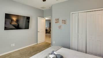 Un dormitorio con cama, ventilador de techo, un cuadro y un pasillo que lleva a un baño.