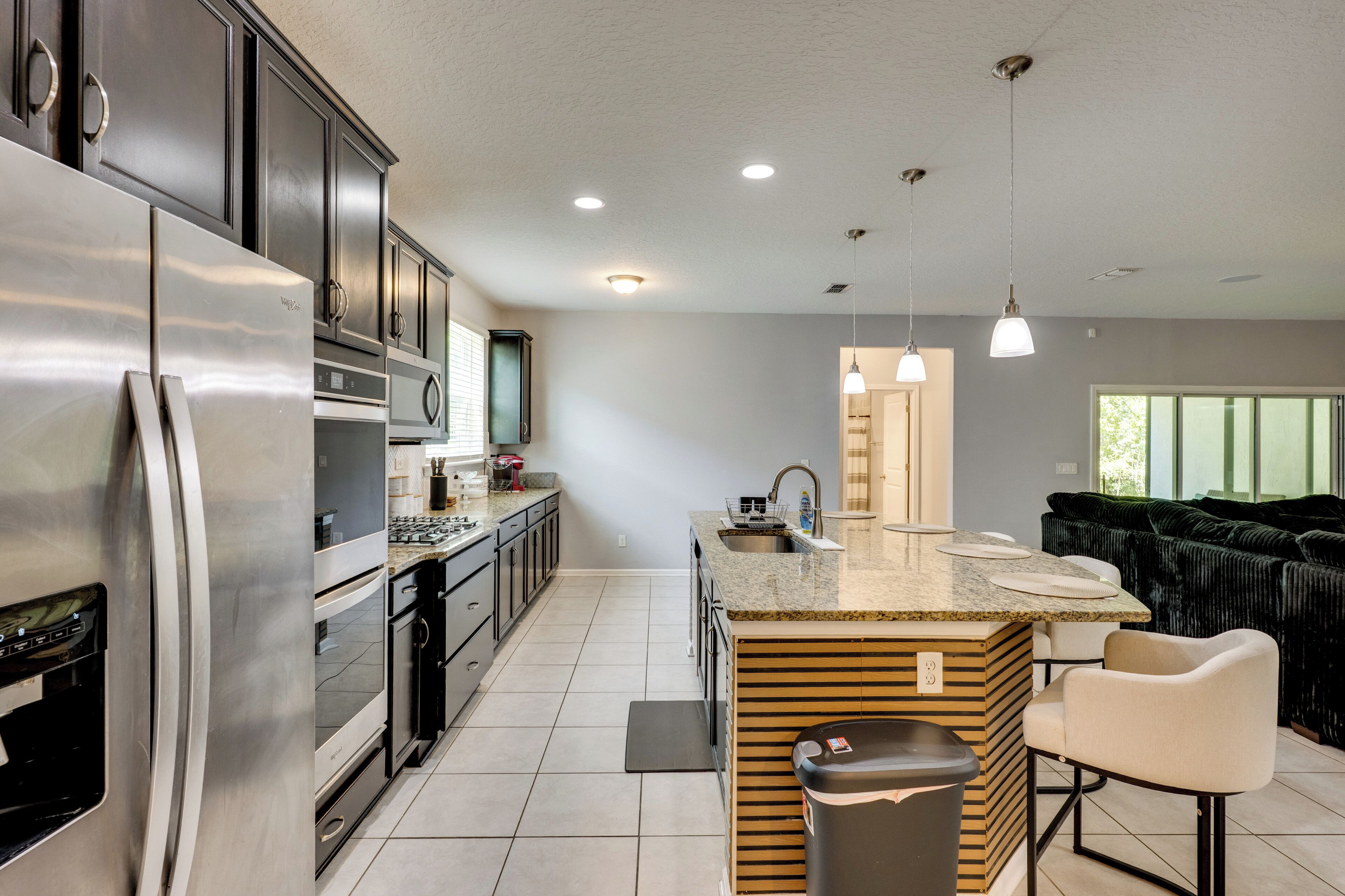 A modern kitchen with stainless steel appliances, a central island, and pendant lighting.