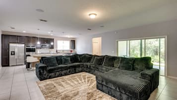 A modern kitchen with dark cabinets, stainless steel appliances, and pendant lighting.
