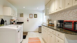 A kitchen with white cabinets, a red microwave, and a tiled backsplash. - Gateway to DC, Waterfalls & More! Mclean Apartment (McLean)
