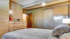 A bedroom with a bed, dresser, and a door.
