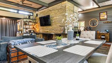 Un comedor con una mesa larga, sillas y una pared de piedra.