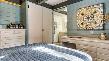 A bedroom with a bed, dresser, and a wall with a decorative piece.