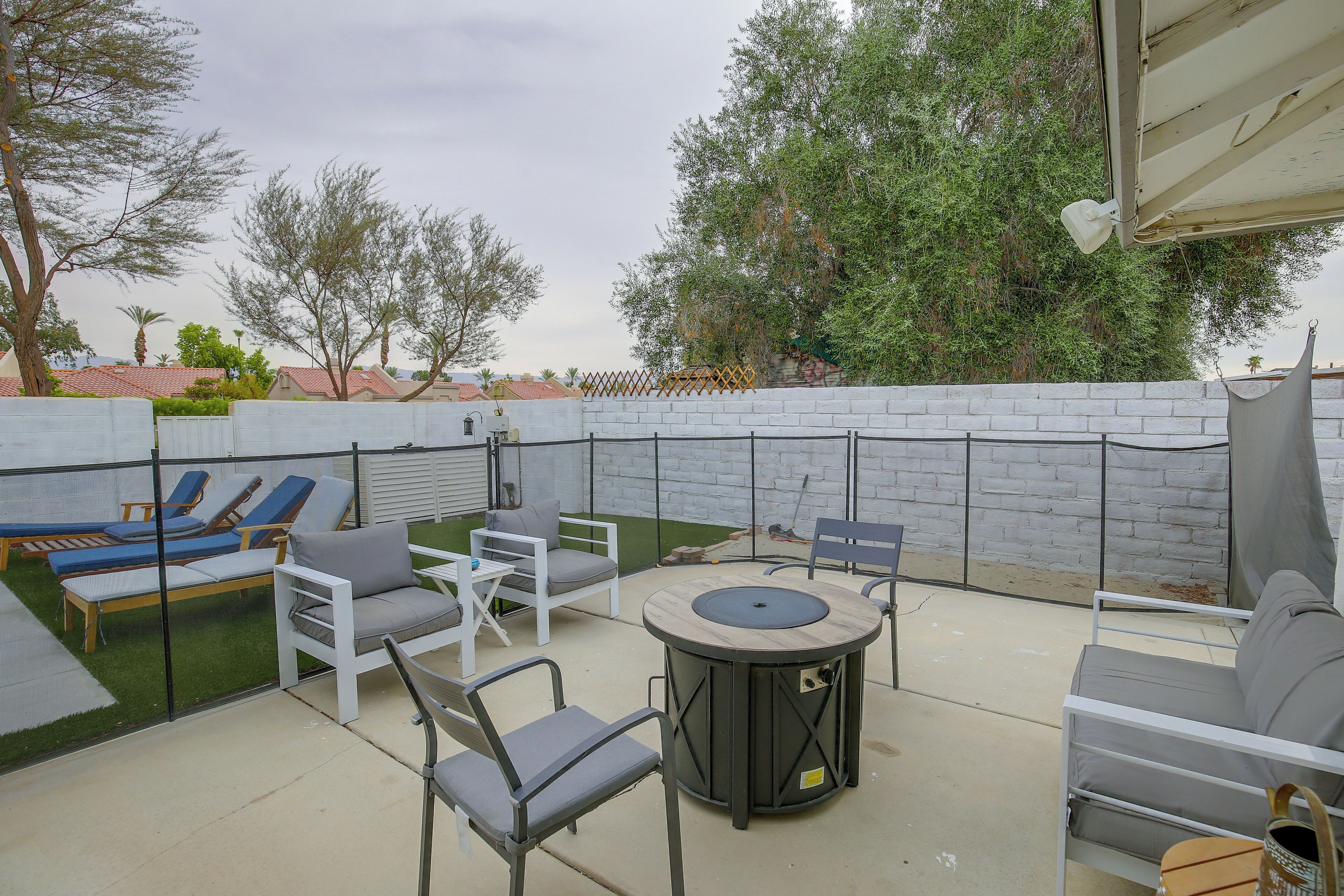 An outdoor patio area with lounge chairs, a table, and a fire pit.
