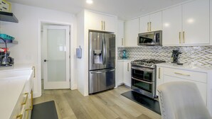A modern kitchen with white cabinetry, stainless steel appliances, and a herringbone tile backsplash. - Grill & Fire Pit! Palm Desert Extended Escape (Palm Desert)