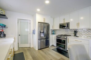 A modern kitchen with white cabinetry, stainless steel appliances, and a herringbone tile backsplash. - Grill & Fire Pit! Palm Desert Extended Escape (Palm Desert)