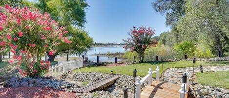 A wooden deck leading to a lake with a white fence and a stone pathway.