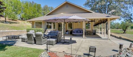A covered patio area with outdoor furniture, a pergola, and a landscaped garden with rocks and mulch.