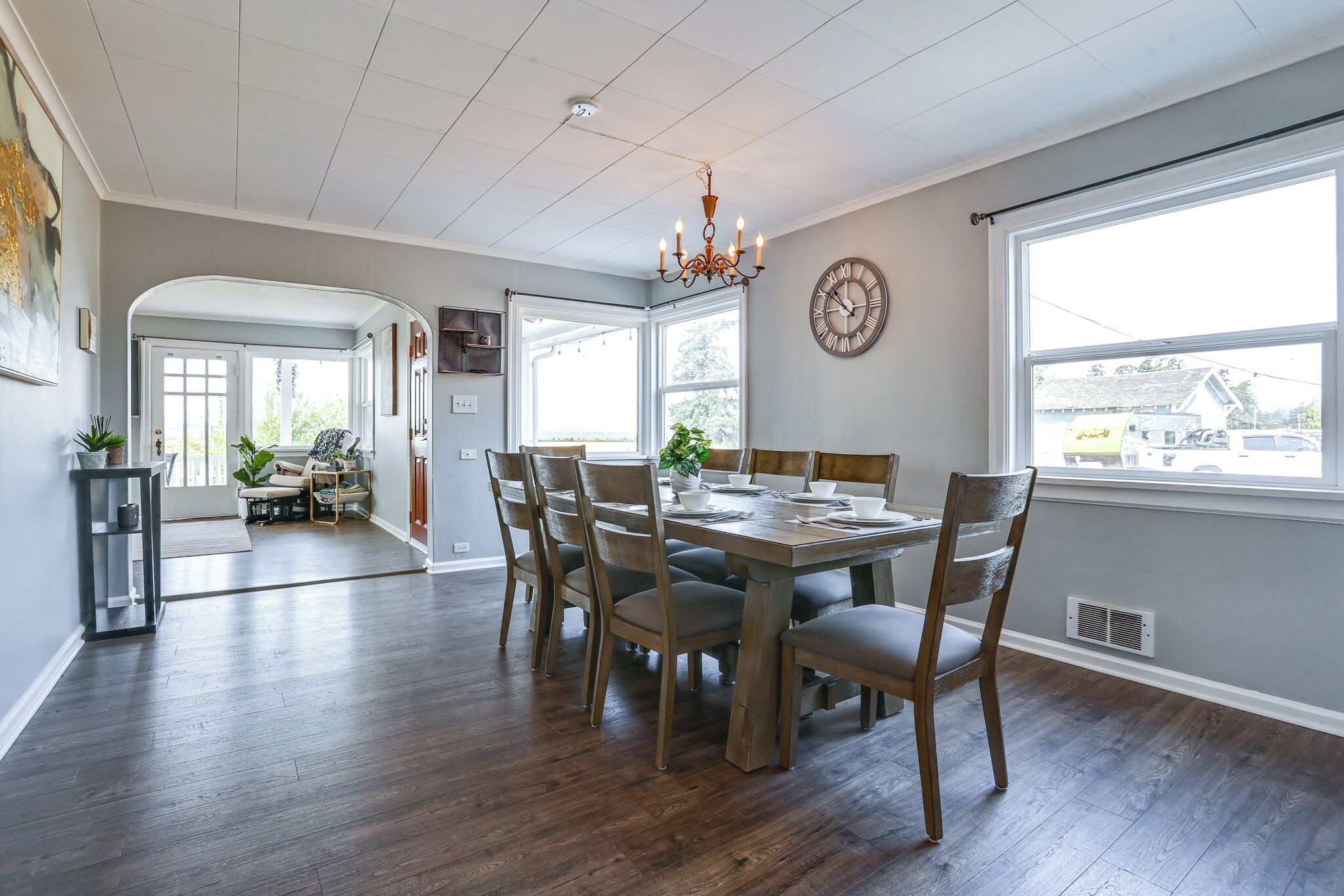 A dining area with a wooden table and chairs, a chandelier, and a clock on the wall.