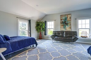 A spacious bedroom with a large bed, a leather sofa, and a potted plant.