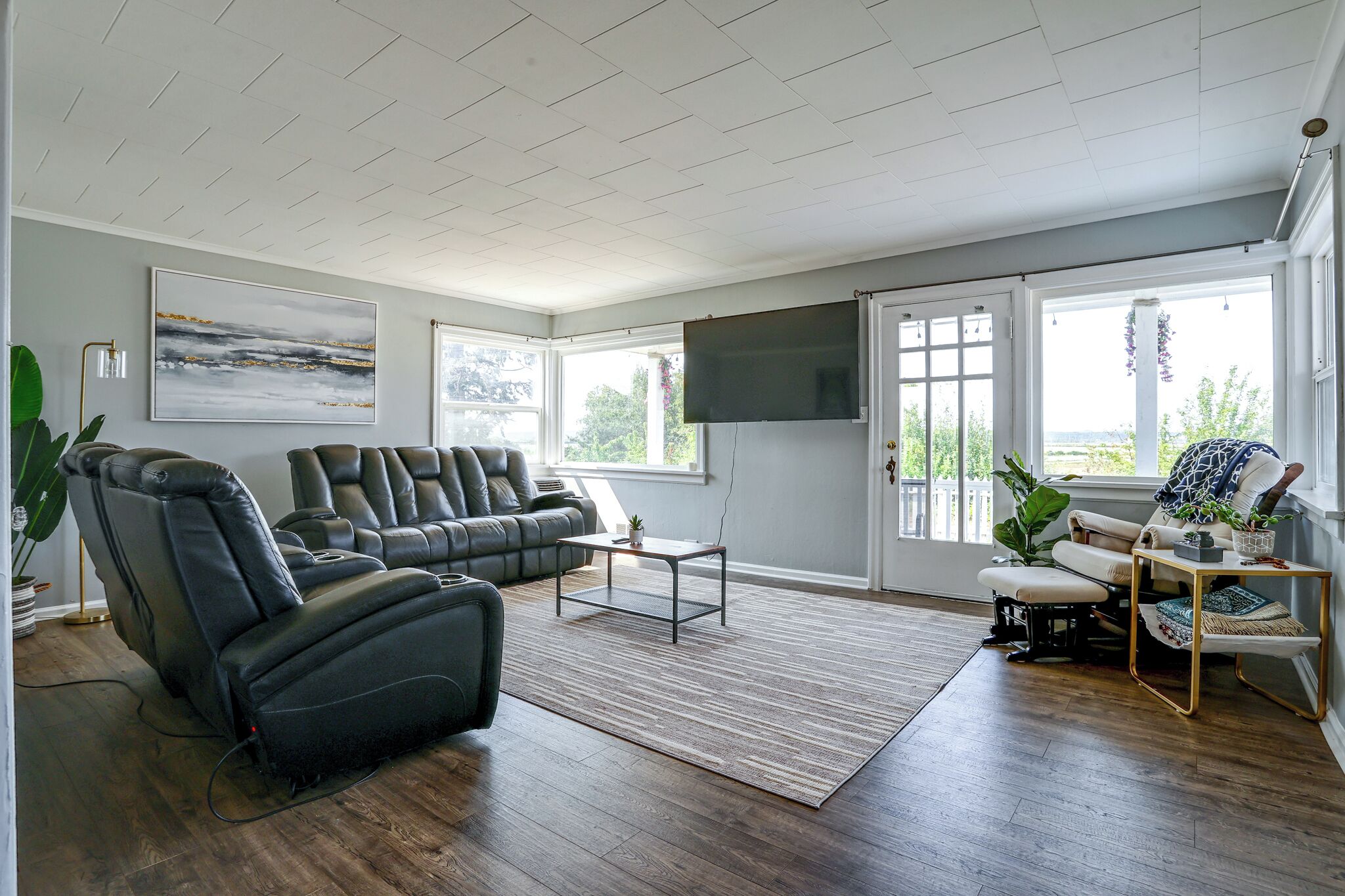 Una sala de estar moderna con un sofá modular, un sillón reclinable, una mesa de centro y un televisor de pantalla plana montado en la pared.