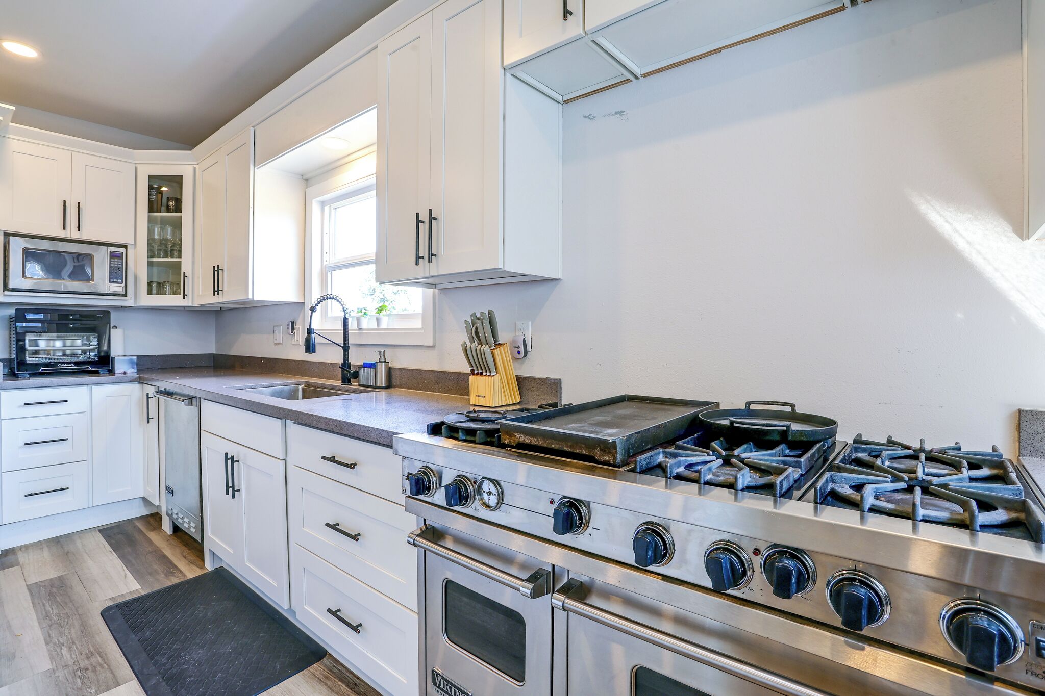 A modern kitchen with white cabinetry, a built-in oven, a gas stove, and a microwave.