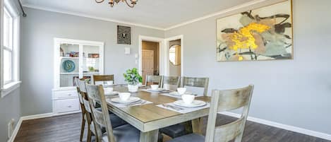 A dining room with a wooden table set for four, surrounded by chairs with cushioned seats.