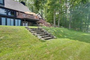 A two-story house with a stone staircase leading to a wooden deck.