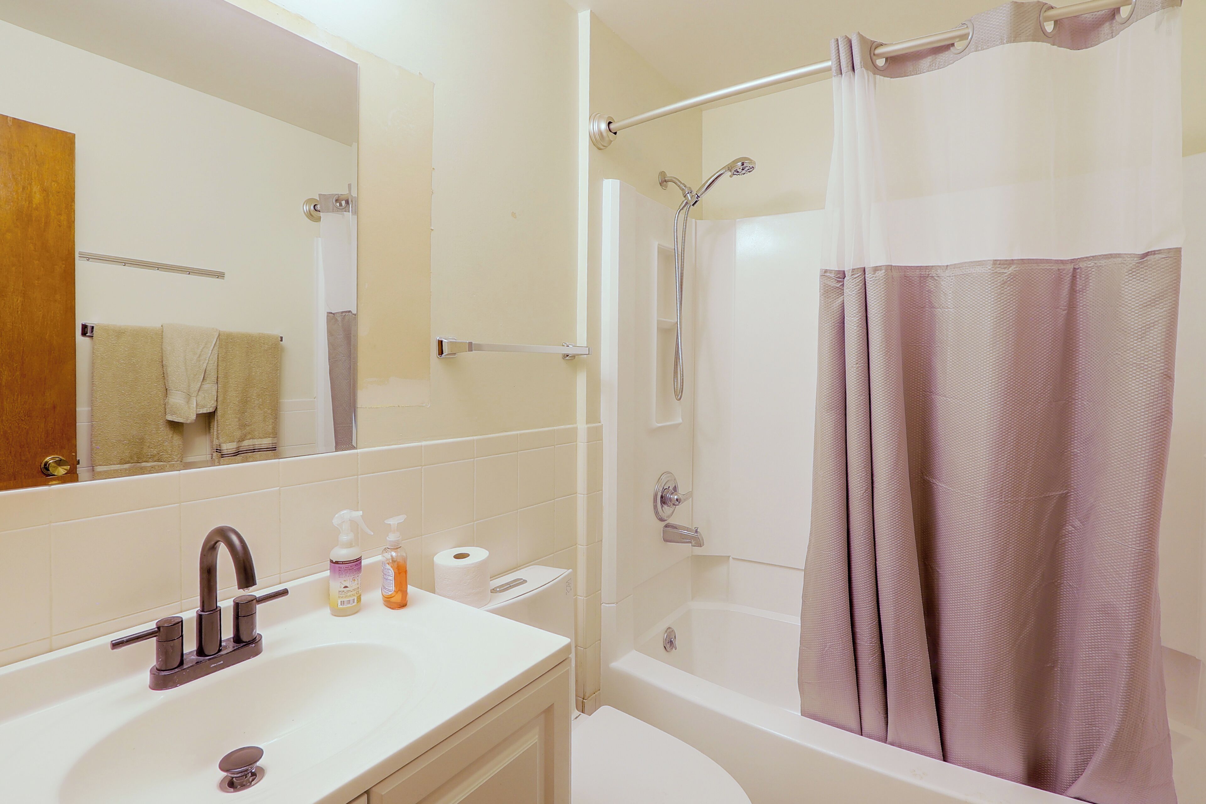 Une salle de bain équipée d’un lavabo, d’un miroir, de toilettes et d’une douche avec un rideau.