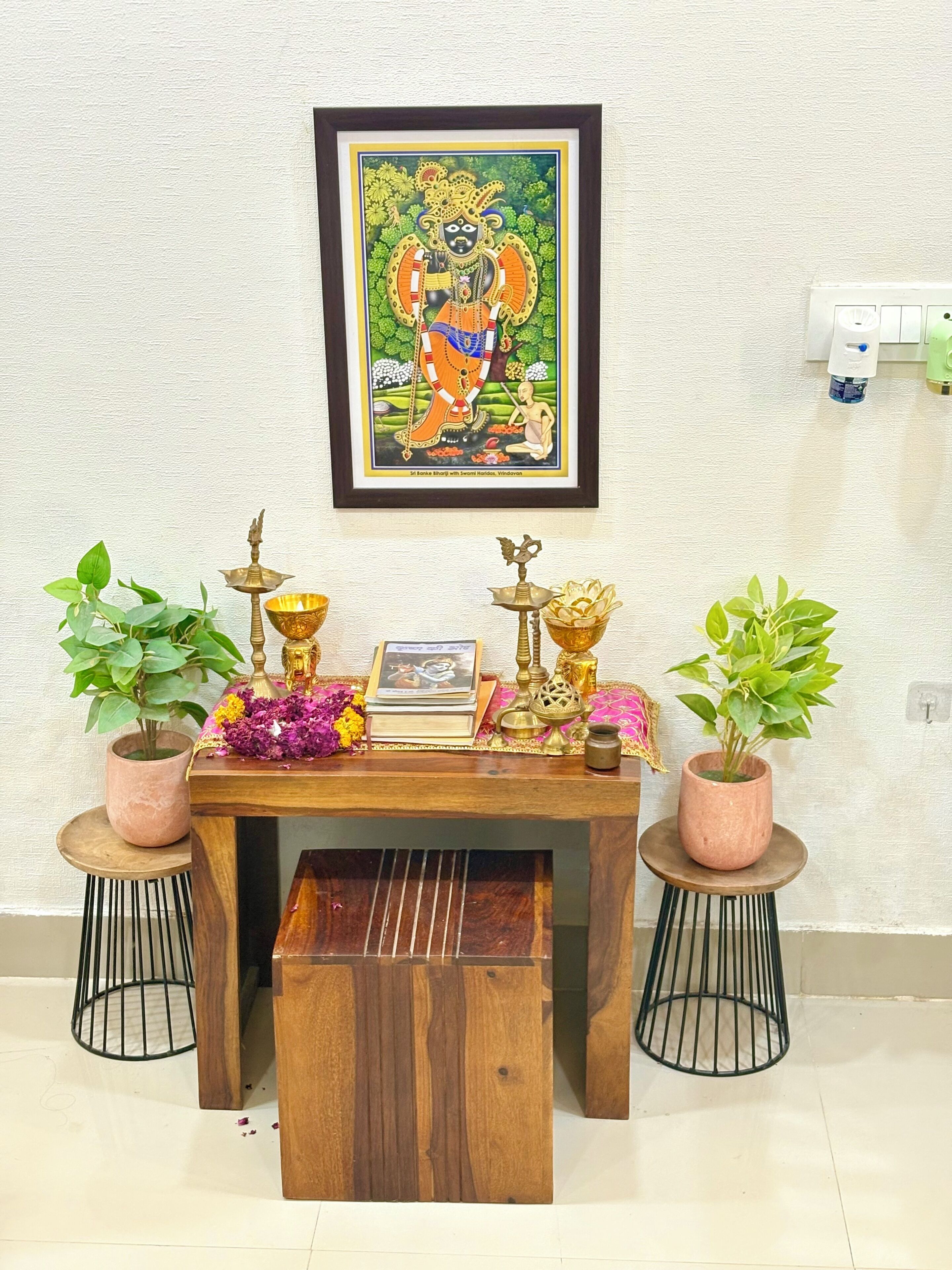 Un altare in legno con icone religiose, un quadro incorniciato sopra e piante in vaso su entrambi i lati.