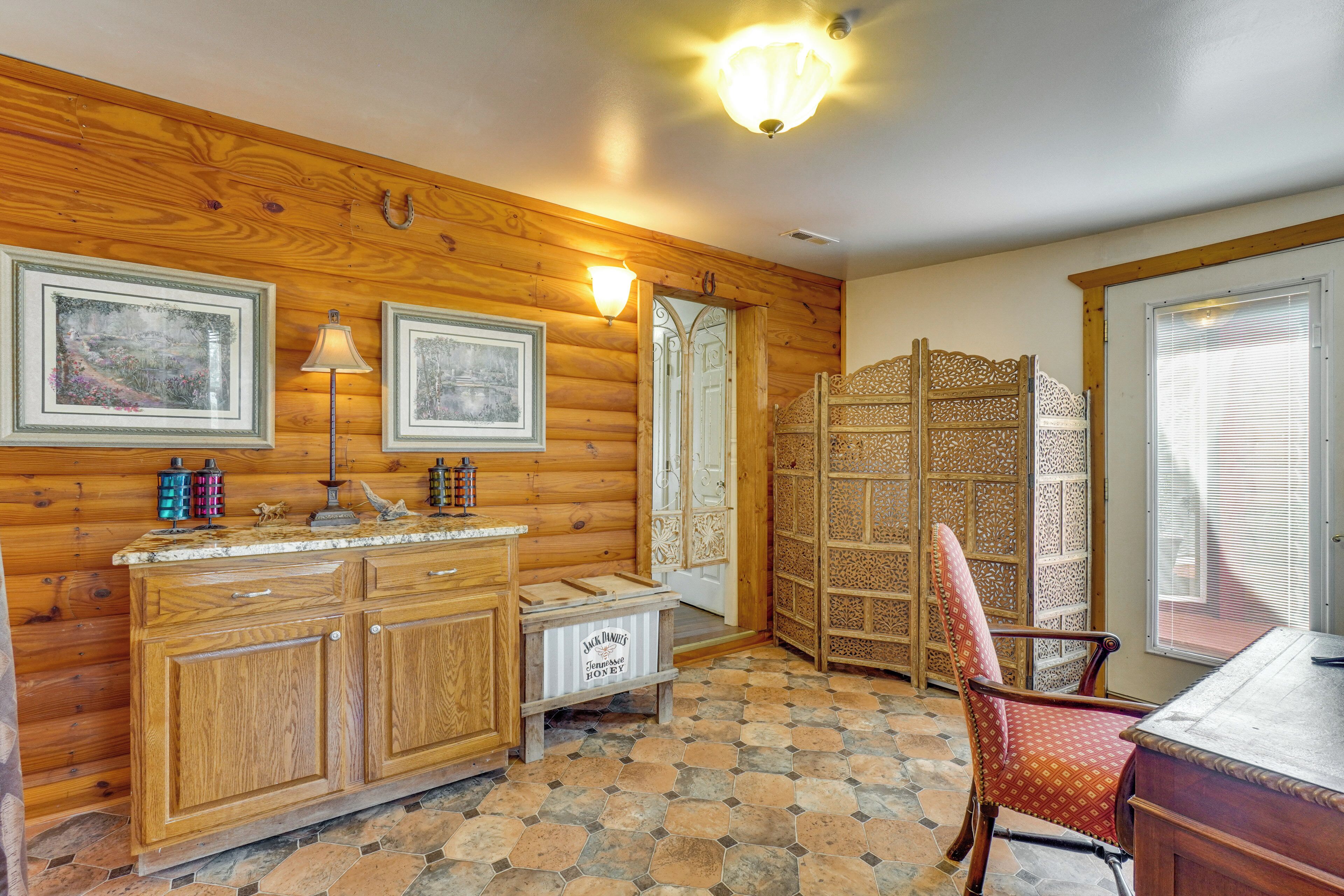 A wooden interior with a stone-tiled floor, a wooden cabinet, a chair, and a decorative screen.