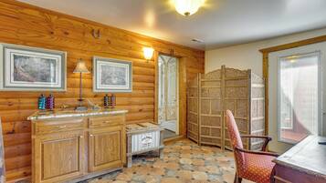 A wooden interior with a stone-tiled floor, a wooden cabinet, a chair, and a decorative screen.