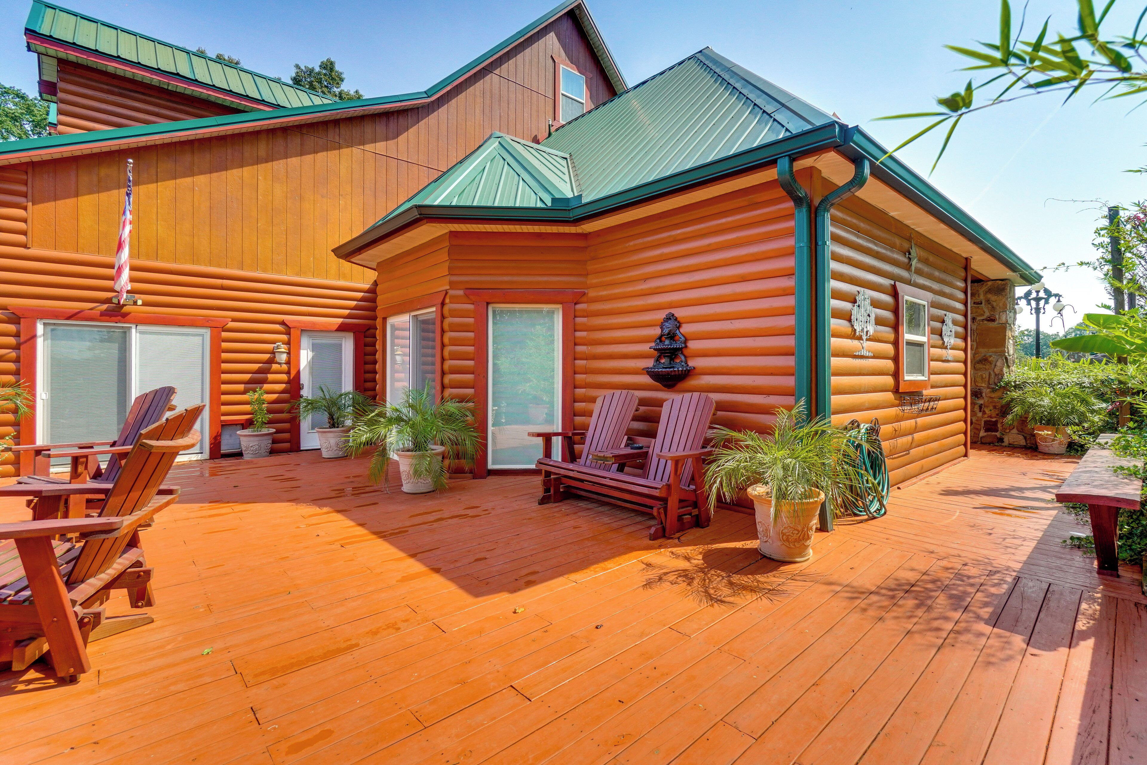 A log cabin with a deck, outdoor seating, and potted plants.