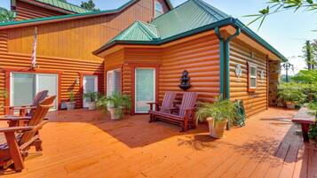 A log cabin with a deck, outdoor seating, and potted plants.