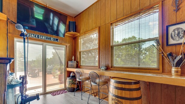 Un interno in legno con un'area bar, ampie finestre e un cartello con la scritta 'Jack Daniel's'.