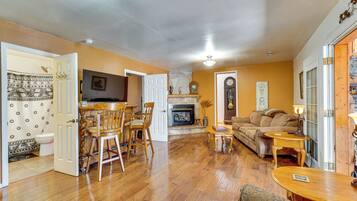A spacious living room with hardwood flooring, a fireplace, a dining area with wooden chairs, and a sofa.