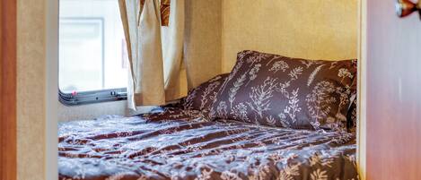 A bedroom with a bed, curtains, and a window.
