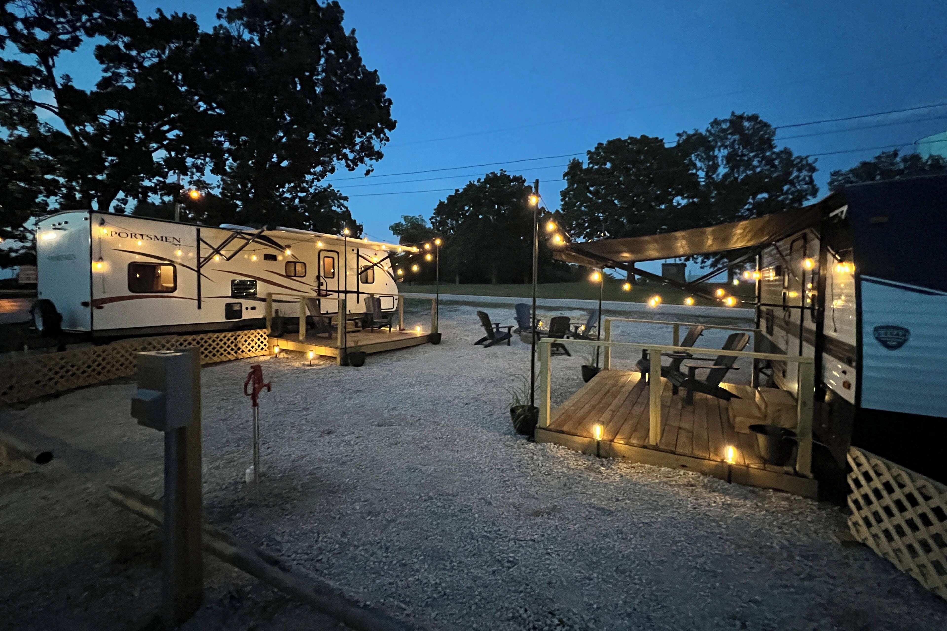 A campsite with RVs and a wooden deck area with seating.