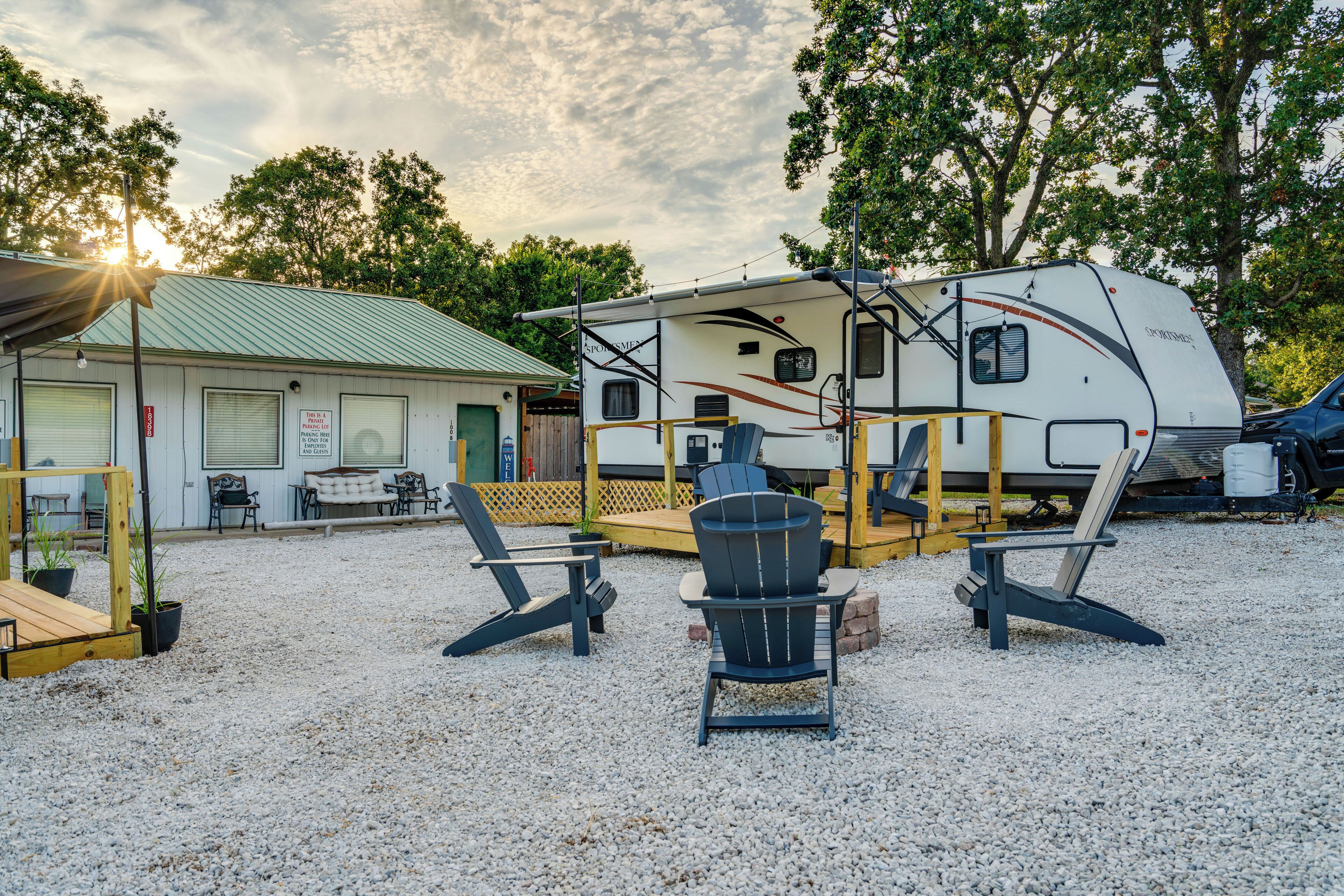 A recreational vehicle (RV) parked in a gravel area with a covered deck and outdoor seating.