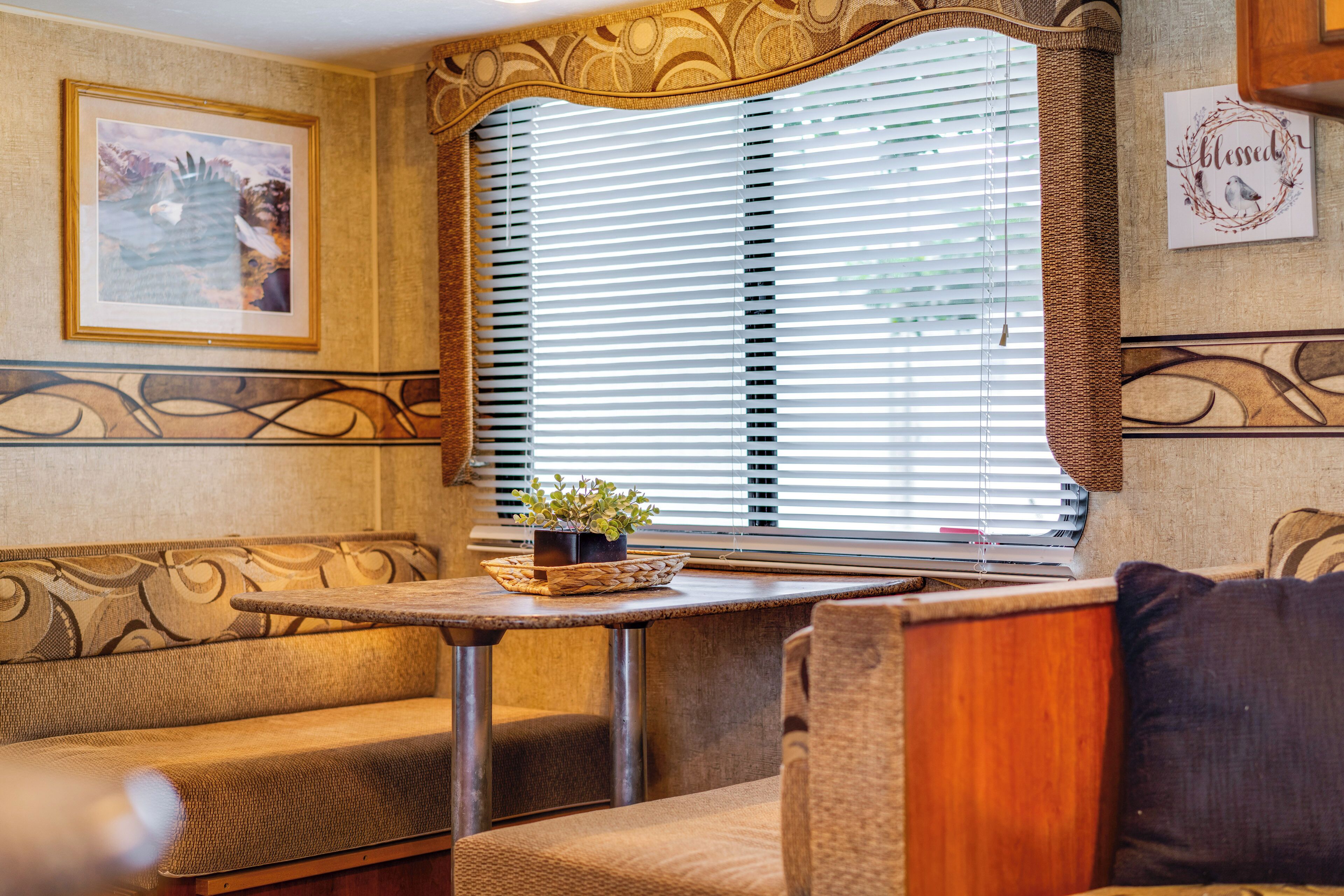 A cozy interior with a sofa, a small table with a plant, and a window with blinds.