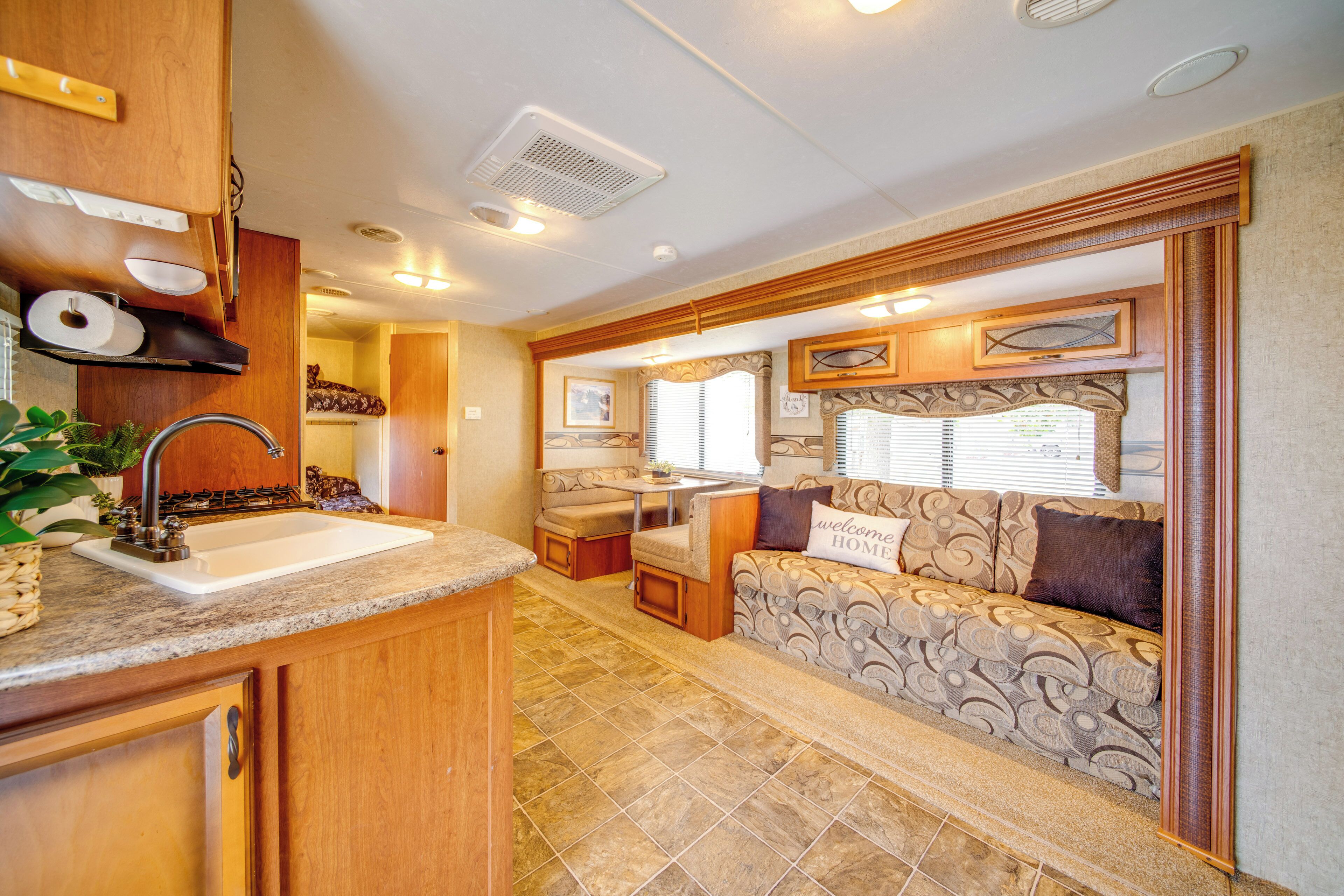 A compact RV interior with a kitchenette, a seating area, and a small dining space.