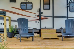 Un espacio de estar al aire libre techado con dos sillas Adirondack y una mesa de madera.
