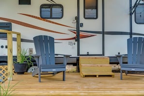 Un espacio de estar al aire libre techado con dos sillas Adirondack y una mesa de madera.