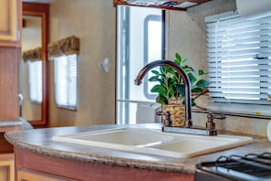 A kitchen with a sink, a window with blinds, and a potted plant.