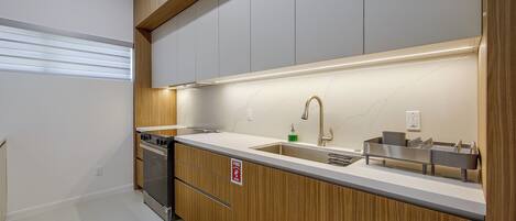 A modern kitchen with wooden cabinetry, a stainless steel sink, and a built-in oven.