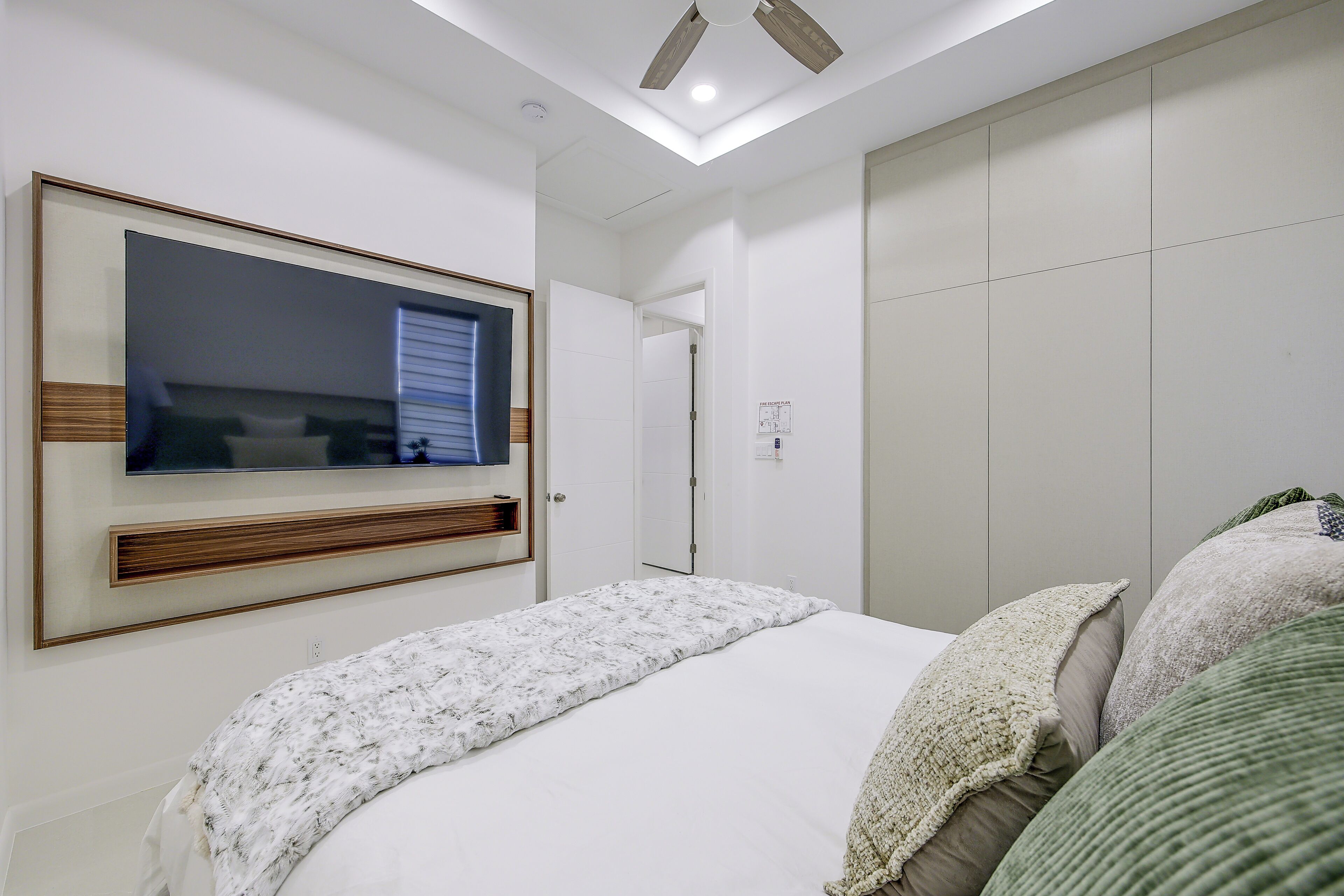 Un dormitorio con cama, televisión montada en la pared y armario.
