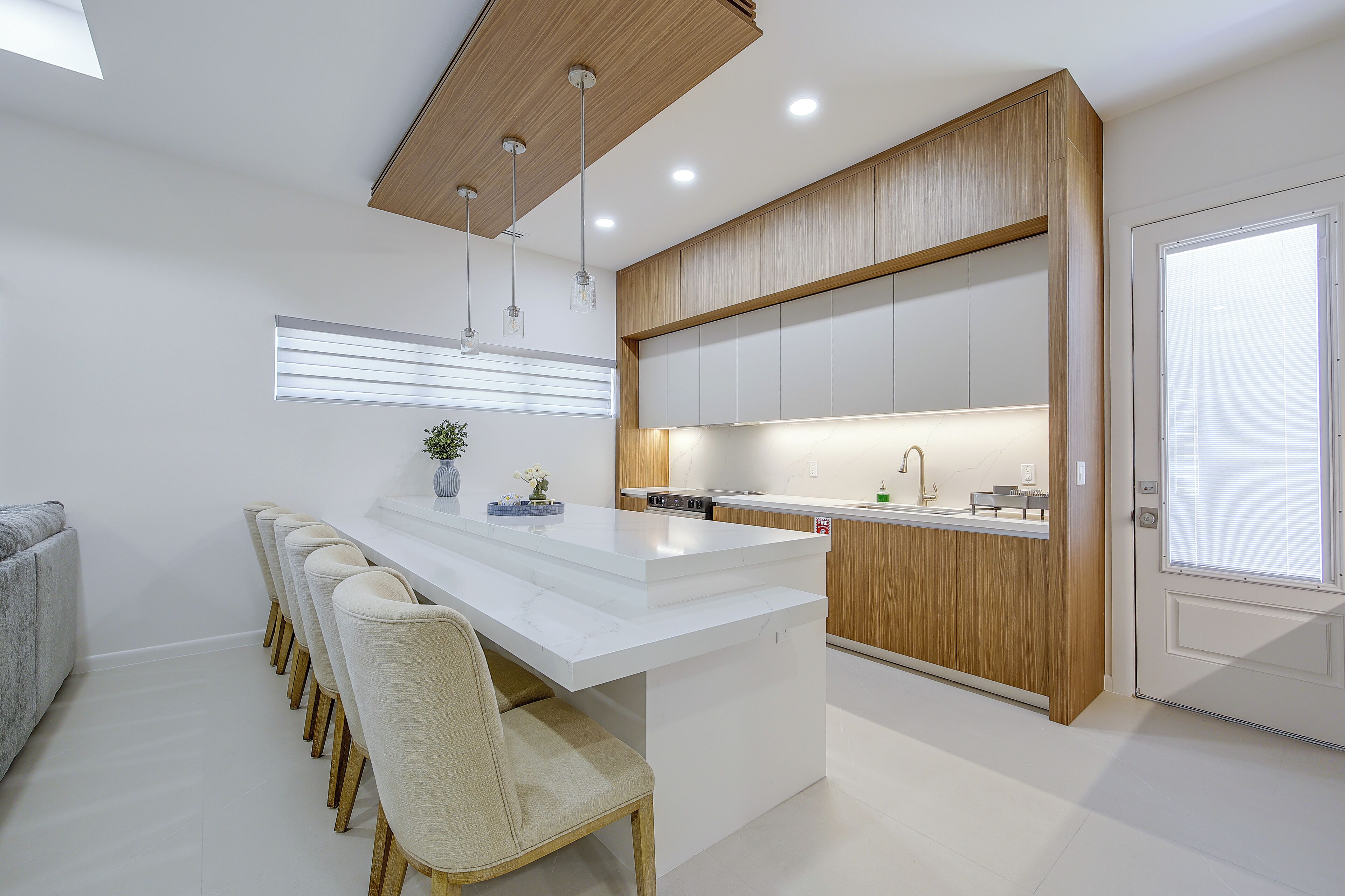 A modern kitchen with a central island, wooden cabinetry, and pendant lighting.