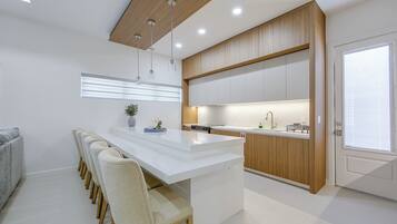 A modern kitchen with a central island, wooden cabinetry, and pendant lighting.