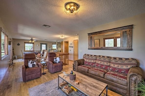 A spacious living room with a wooden floor, leather sofas, a coffee table, and a large mirror on the wall.