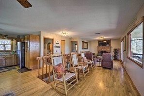 A spacious living area with wooden flooring, a fireplace, and a dining area with wooden chairs.