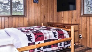 A wooden-paneled room with a bed, a television, and a sign that says 'Go Jump Lake.' - Welcome to Sunset Cove, in the center of Wisconsin's scenic Northwoods. (St.Germain)
