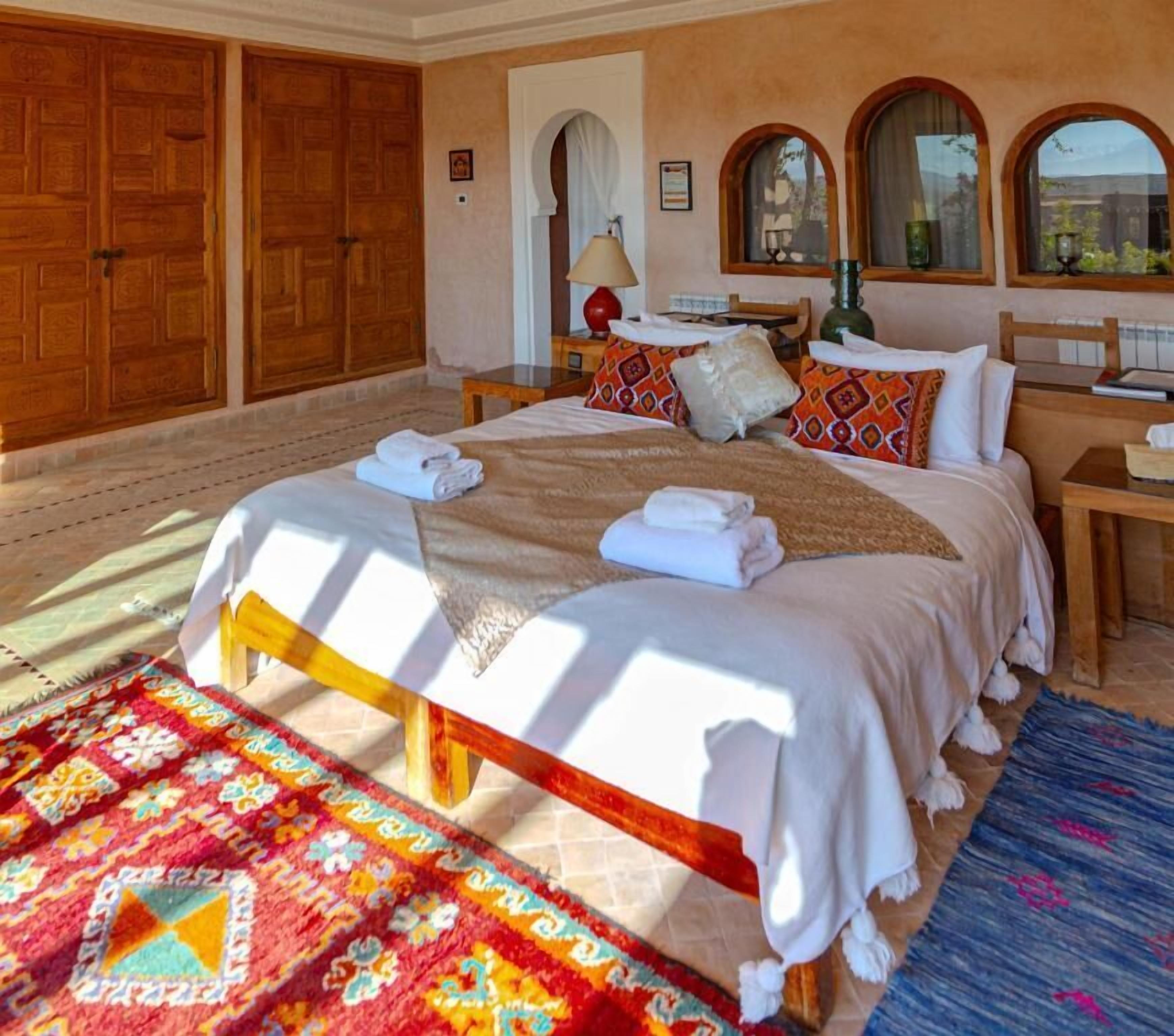 A spacious bedroom with a large bed, wooden wardrobe, and a view of the outdoors.