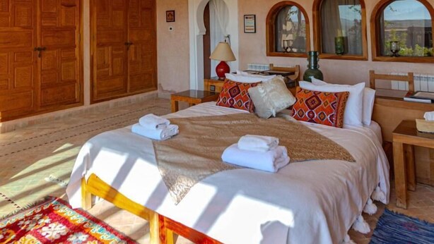 Un dormitorio amplio con una cama grande, armario de madera y vistas al exterior.