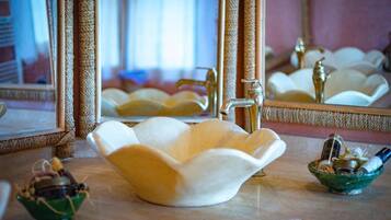 Un baño con un lavabo blanco con forma de flor, un espejo y dos recipientes pequeños sobre la encimera.
