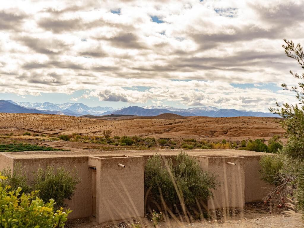 A desert landscape with mountains in the background, a concrete structure in the foreground, and sparse vegetation.