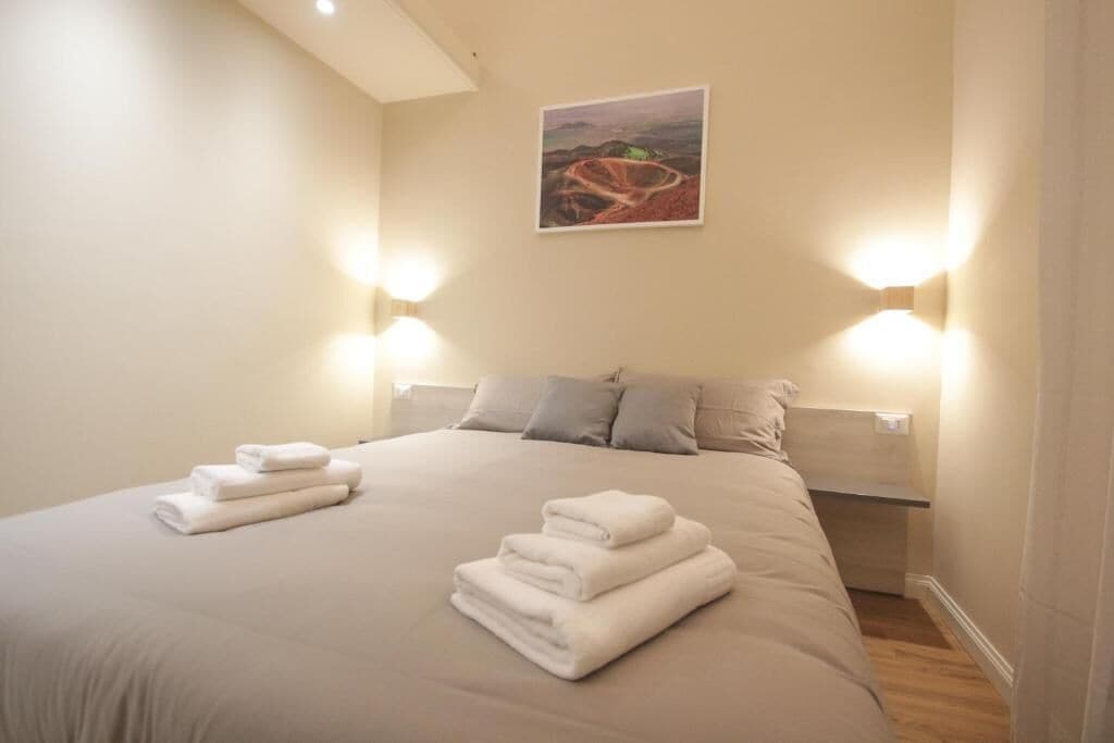 Une chambre d’hôtel avec un grand lit, deux lampes fixées au mur et un tableau accroché au mur.